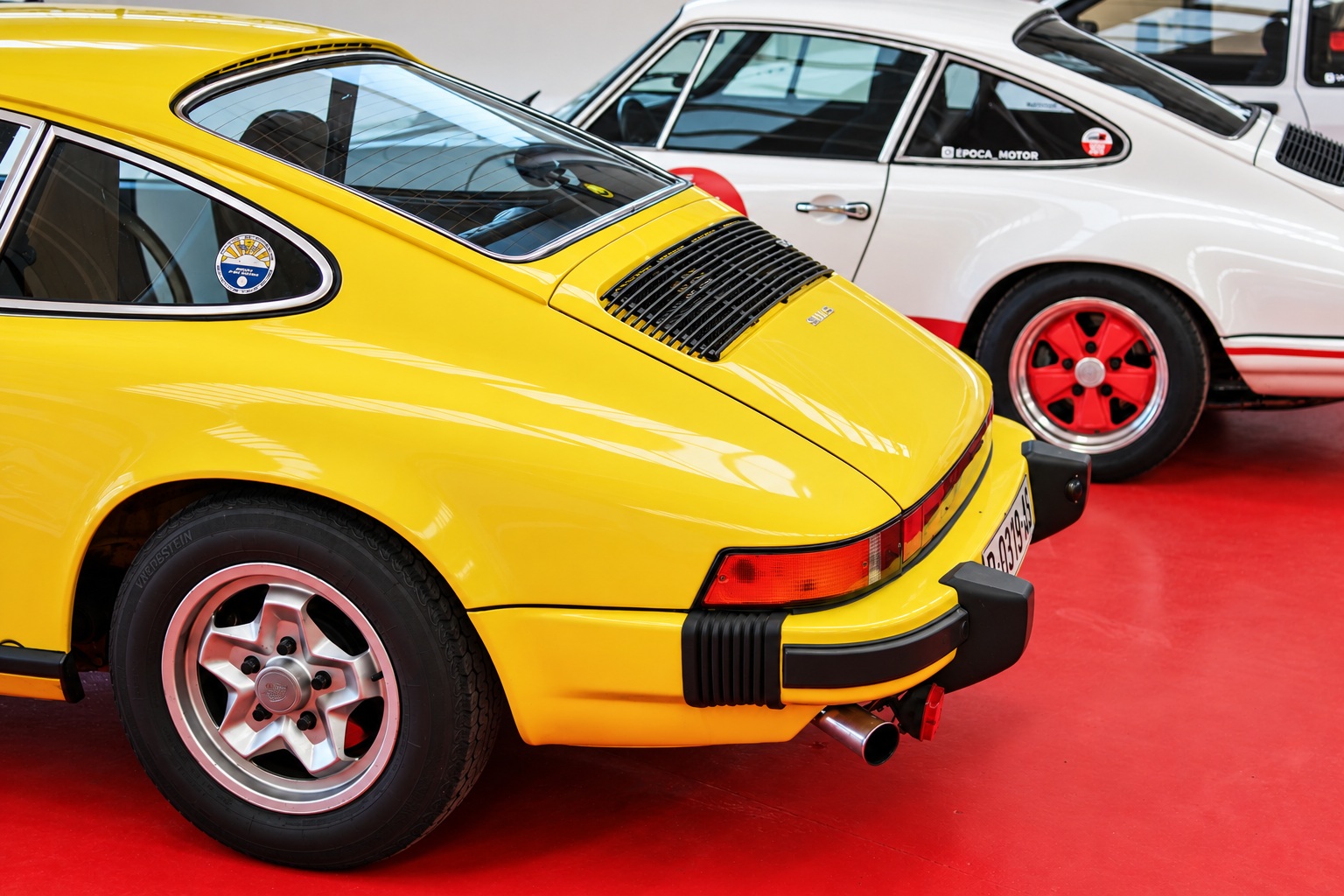 Porsche 911 amarillo y Porsche blanco en la exposición de Época Motor