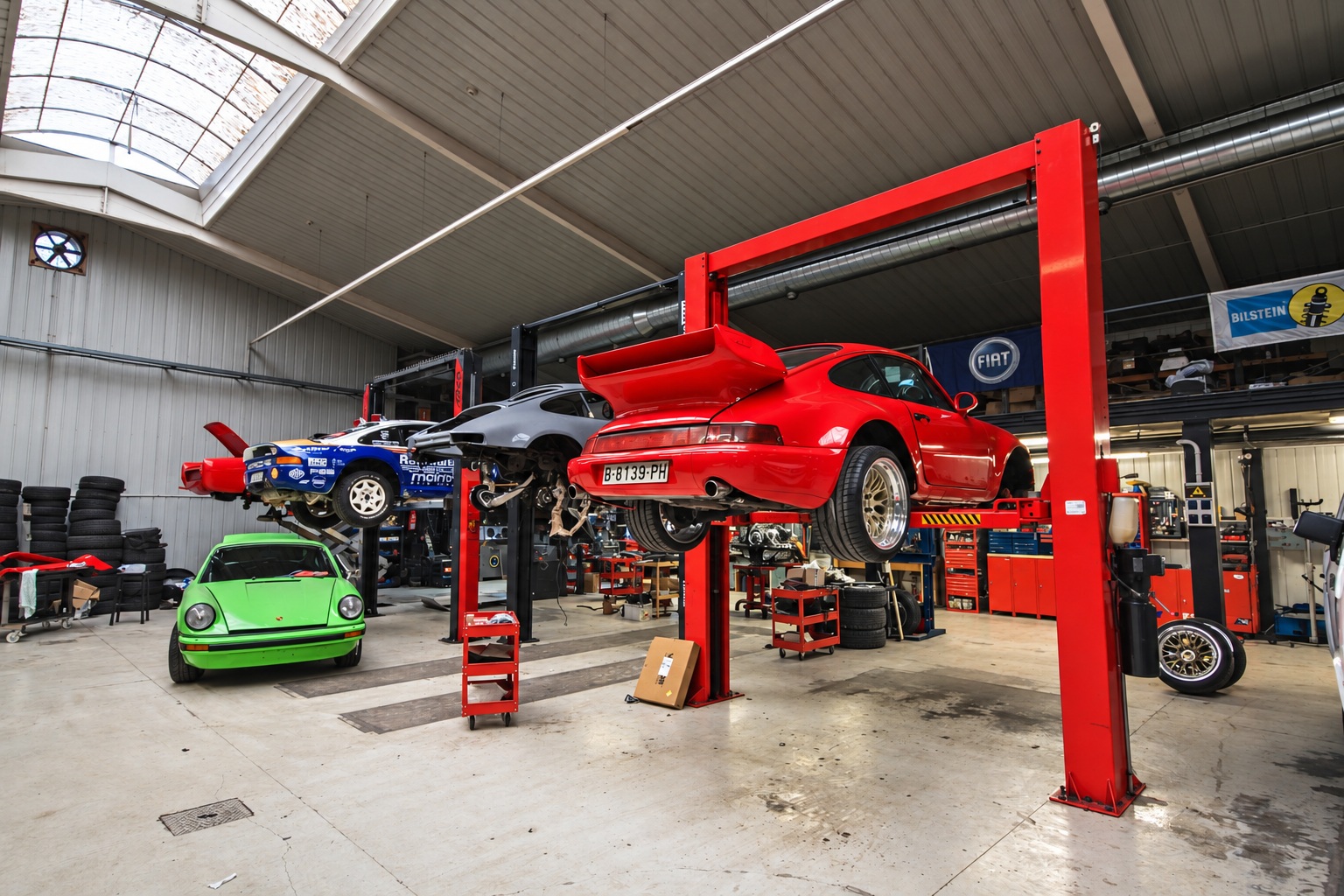 Ferrari Testarossa y Porsche clásicos en el taller de Época Motor, con la zona de trabajo ordenada
